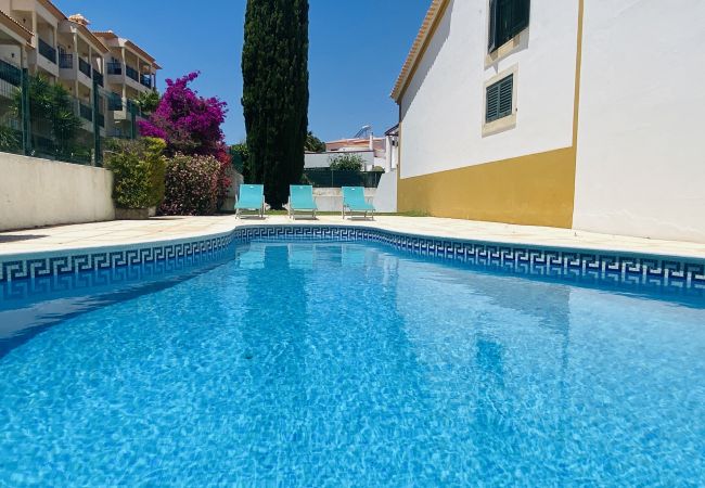 Piscina partilhada com água azul, zona envolvente em pedra e espreguiçadeiras numa casa em Olhos de Água, Albufeira