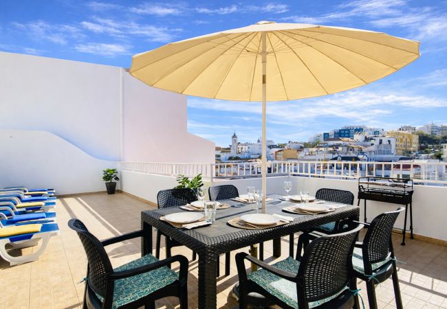 Terraço amplo com mesa de refeições ao ar livre, espreguiçadeiras e vista urbana no centro de Albufeira